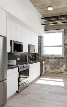 A kitchen with stainless steel appliances and wooden floors.