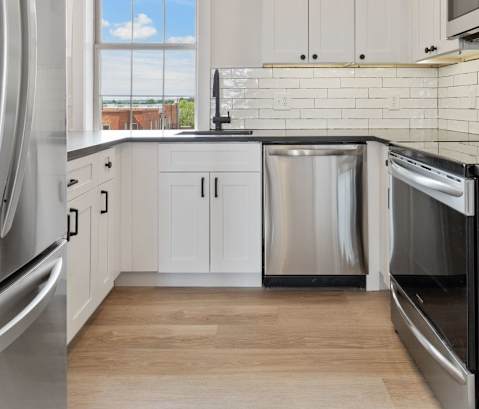 a white kitchen with stainless steel appliances and white cabinets