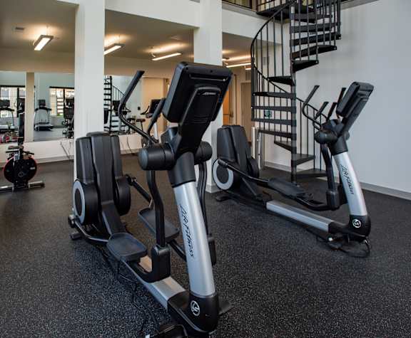 A gym with a row of treadmilers and a staircase in the background at 42 Hundred On The Lake, St Francis, 53235