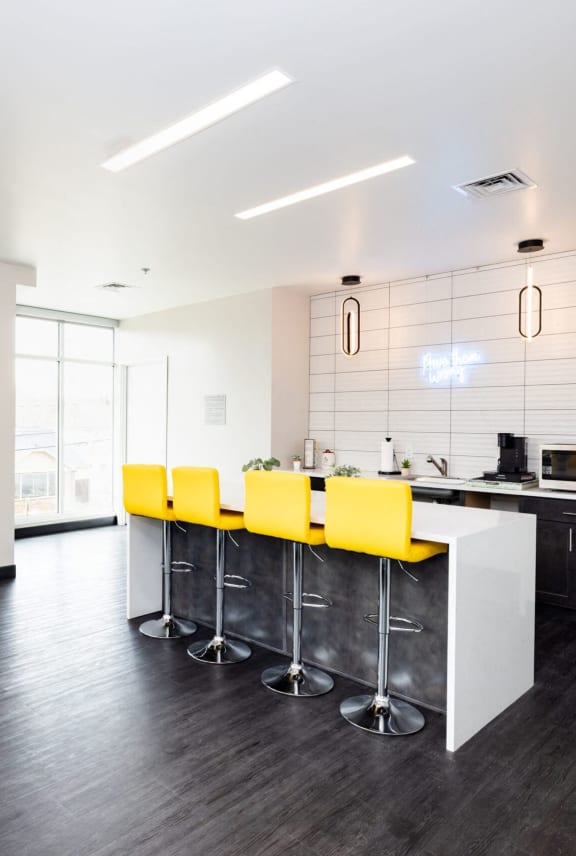 a kitchen with a bar and yellow chairs in a large room