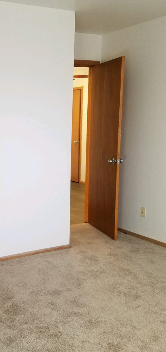 an empty room with two doors and a door to a hallway