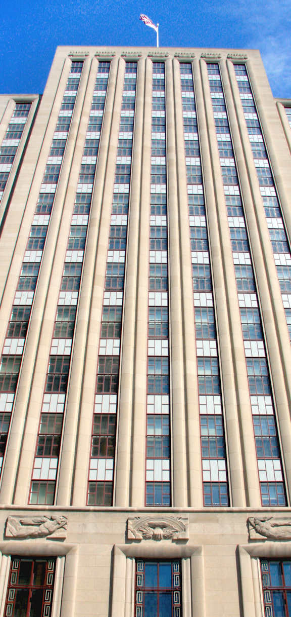 A tall building with a flag on top and a clear blue sky.