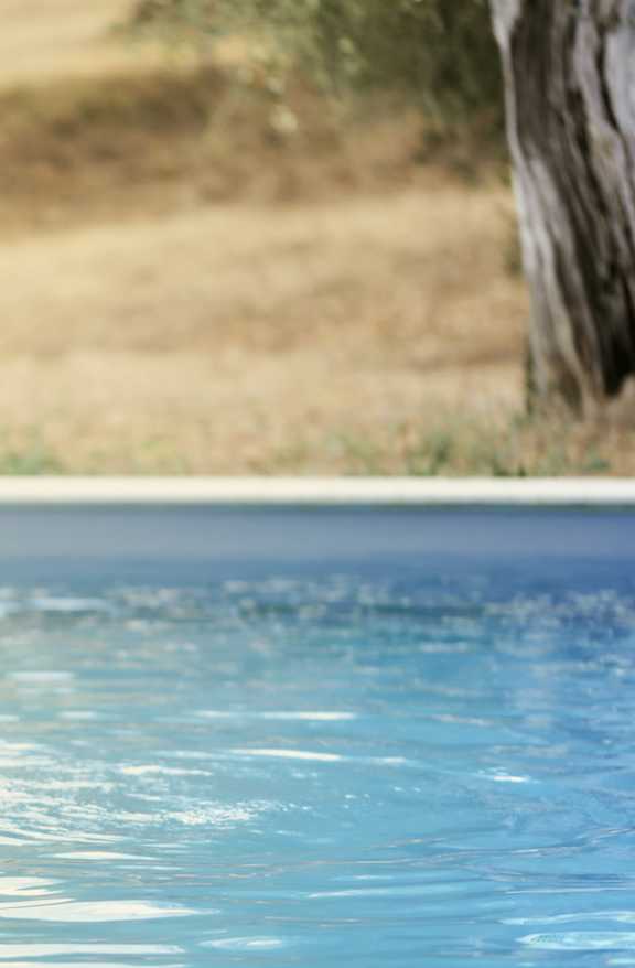 A woman in a white bikini is sitting on the edge of a pool.