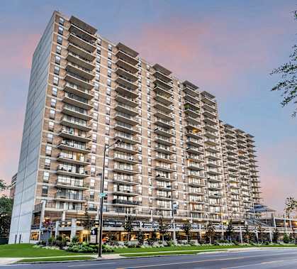 A tall residential building with many windows is situated on a street corner at PREMIER @ CITY LINE, Philadelphia, Pennsylvania