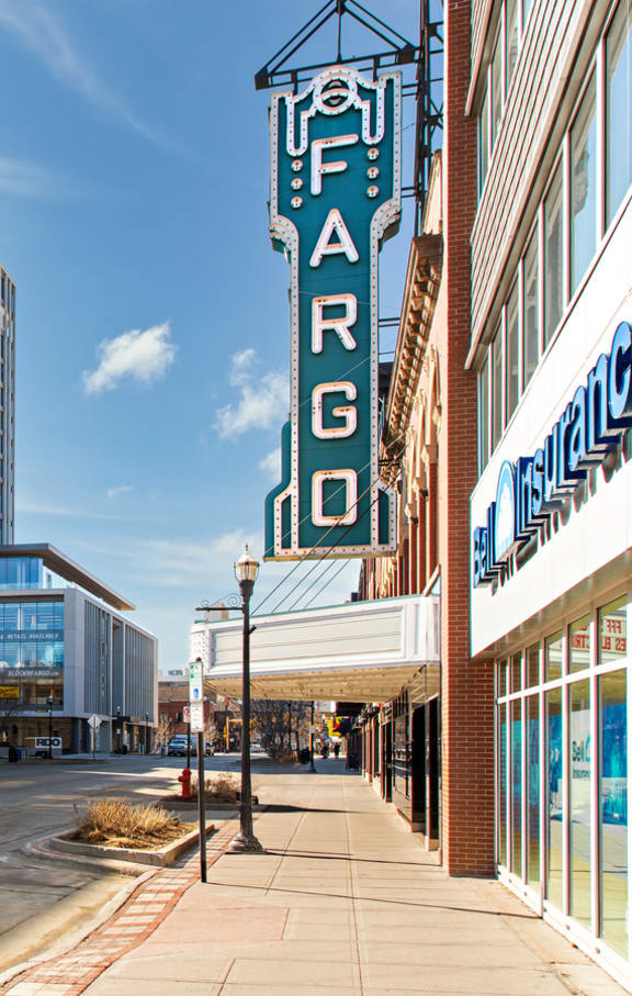 A view of a city street with a large neon sign on the side of a building at Mercantile on Broadway, Fargo, ND, 58102