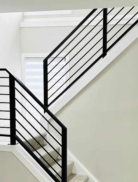 A staircase with a black railing and a white door at Eton Square Apartments and Townhomes, Michigan