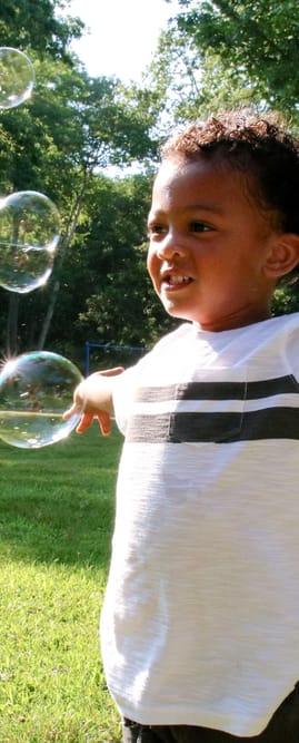 a young boy blowing bubbles in a park