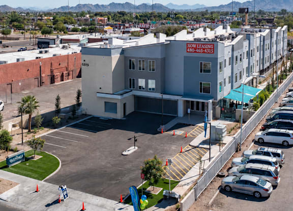 A parking lot with cars and a building with a red sign in the background.