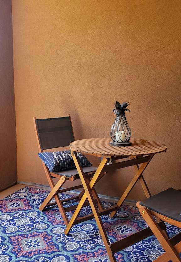 A table with a vase on it and two chairs with a patterned carpet.