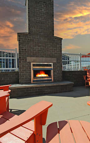 A fireplace is surrounded by red chairs and tables.