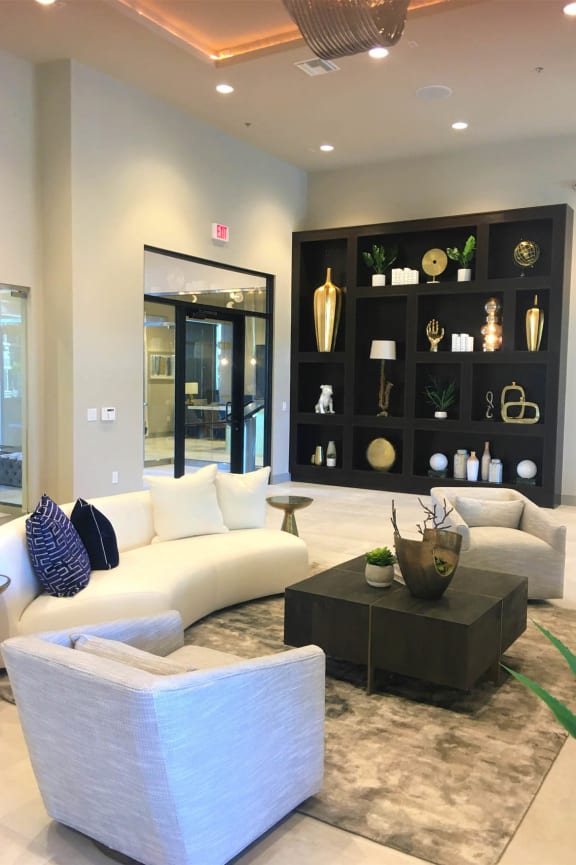 a living room with white furniture and a black display case