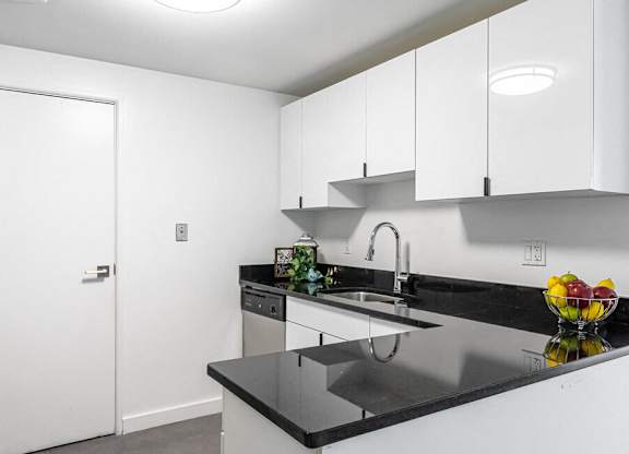 A kitchen with black countertops and white cabinets.