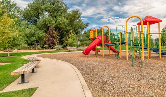 A playground with a red slide and green and yellow play equipment.