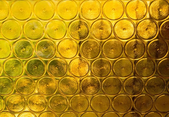 a wall of wine glasses filled with gold liquid