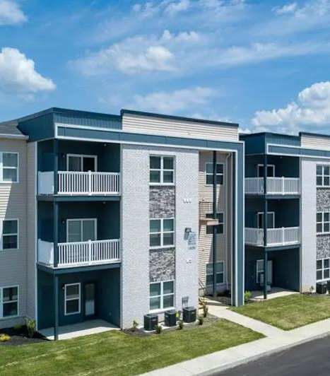 A row of modern apartment buildings with a parking lot in front.