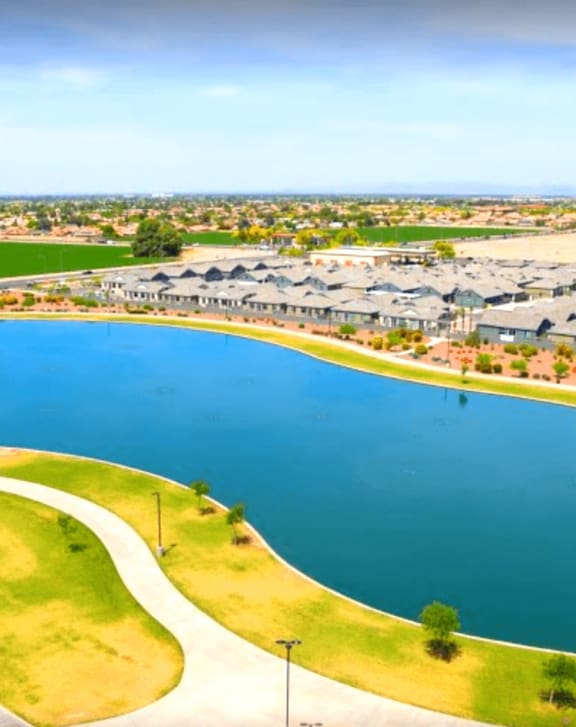 Aerial view of a lake and a grassy area with buildings in the background at Villas on Olive in Peoria, AZ 85345