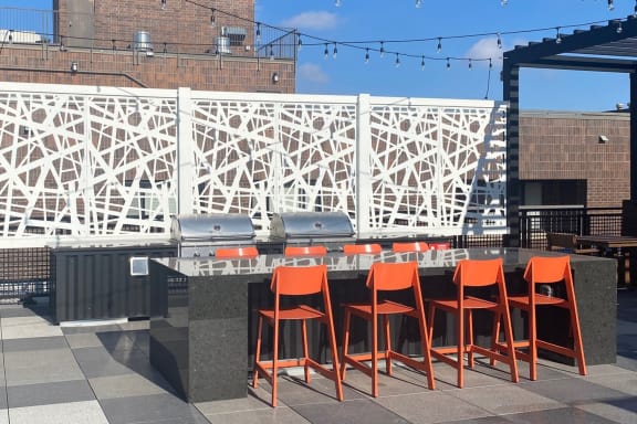 a bar with orange chairs on a patio with a building in the background