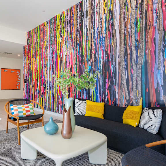 A room with a colorful wallpaper and a couch with pillows.