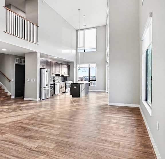 A large open living space with wood flooring and white walls.