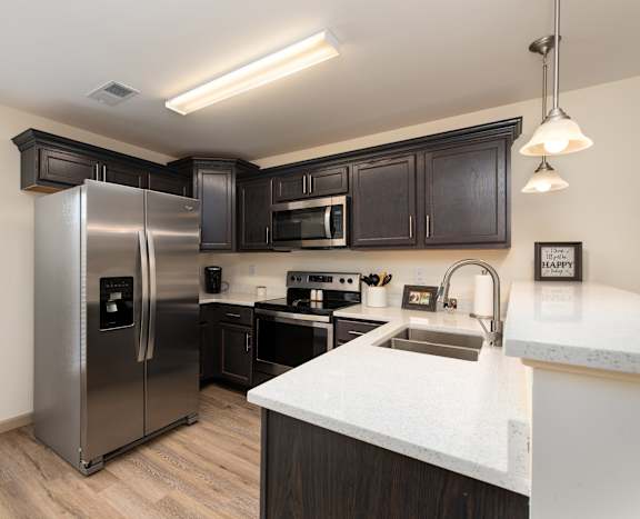 A kitchen with a stainless steel refrigerator and black cabinets.