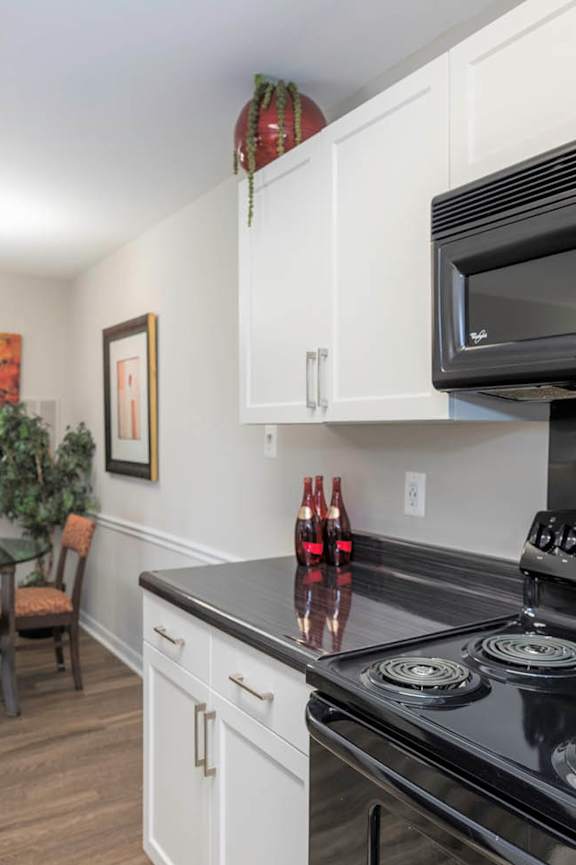 A black stove top oven sits under a microwave in a kitchen.