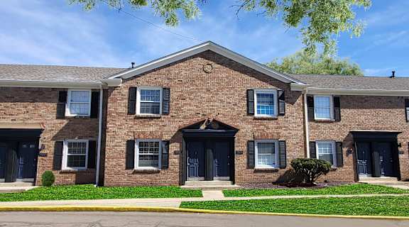 Apartment building with blue doors and windows under a clear sky.