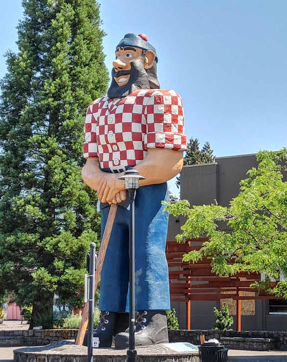 A statue of a man in a red and white checkered shirt stands in front of a building.