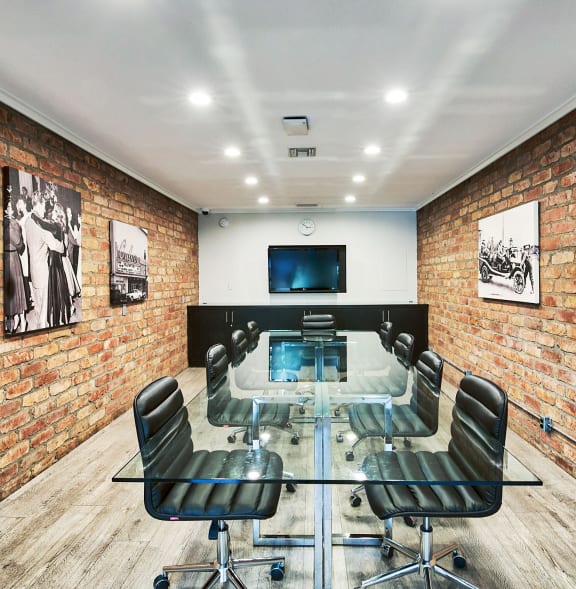 a conference room with a glass table and chairs and a television on the wall at The Meadows Apartments, Culver City , CA 90230