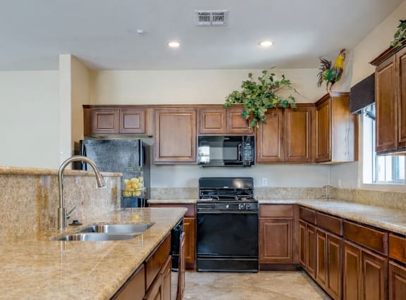 A kitchen with a marble countertop and wooden cabinets.