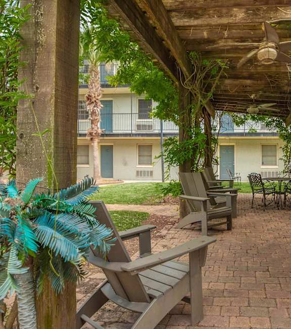 A patio with a table and chairs under a roof. at The Cove at State Street Apartments, Baton Rouge, LA, 70802
