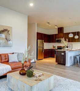 A living room with a couch, a coffee table, and a painting of horses on the wall.