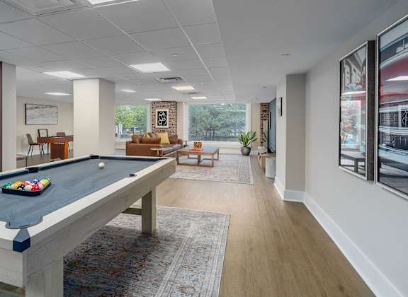 A pool table is in the middle of a room with a couch and a chair.