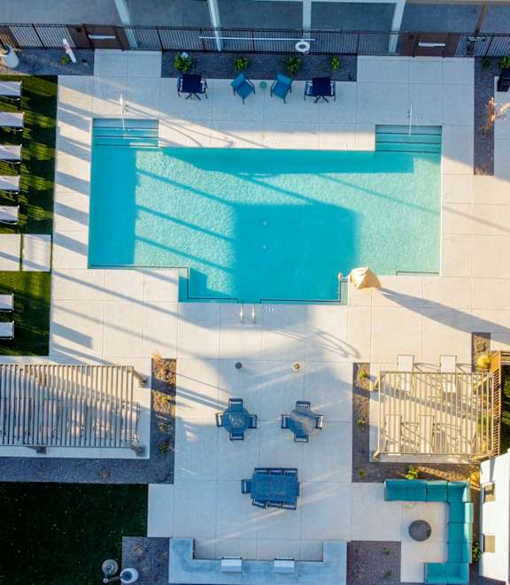 An aerial view of a swimming pool surrounded by a fence and a building.
