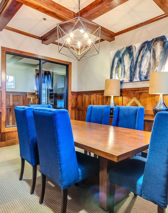 a conference room with wood paneling and a wooden table with blue chairs
