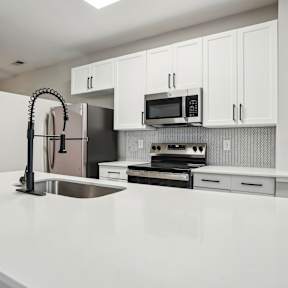 A kitchen with a white counter and a brown chair.