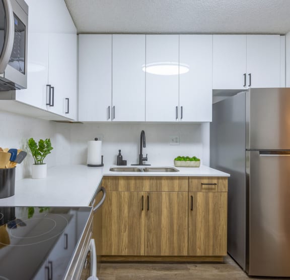 a modern kitchen with white cabinets and stainless steel appliances  at Club at Emerald Waters, Hollywood, Florida
