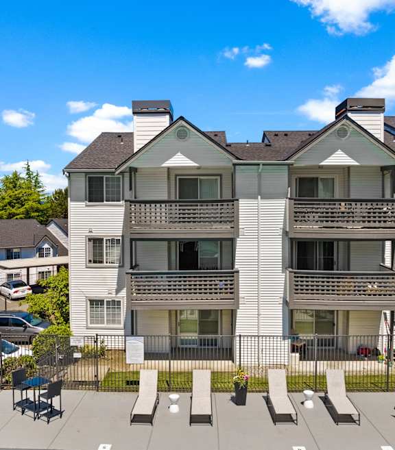 A large white apartment building with a balcony on the second floor.
