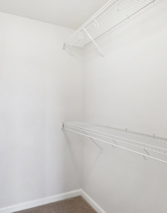 an empty closet with white walls and a hanging rack on the wall