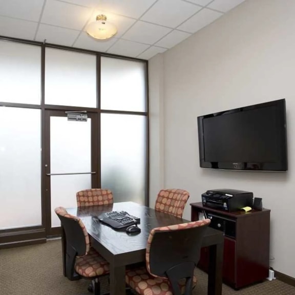 a conference room with a table and chairs and a television