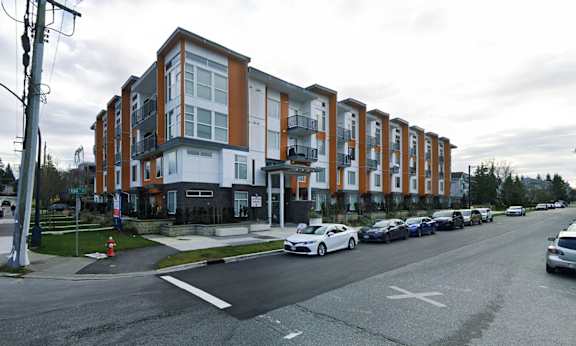 A street view of a building with cars parked on the side of the road.