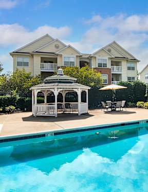 a swimming pool with a gazebo and a house in the background