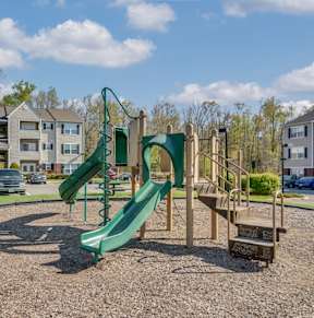 A playground with a green slide and a wooden structure.