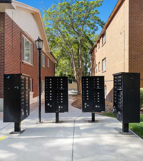 Four black parking meters are lined up on a sidewalk.