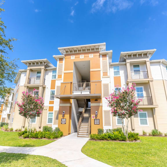 an exterior view of an apartment building with grass and trees