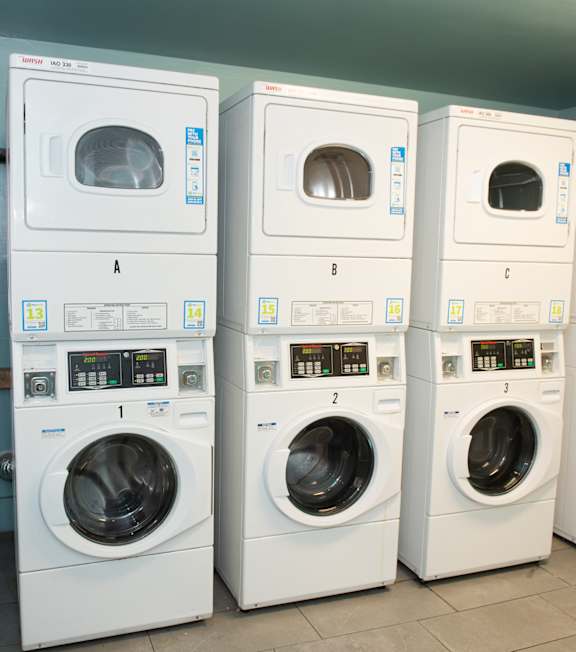 A row of white front load washing machines in a laundromat.