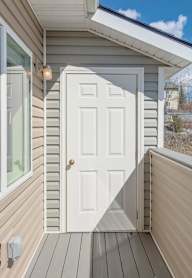 A small white door is on the side of a house.
