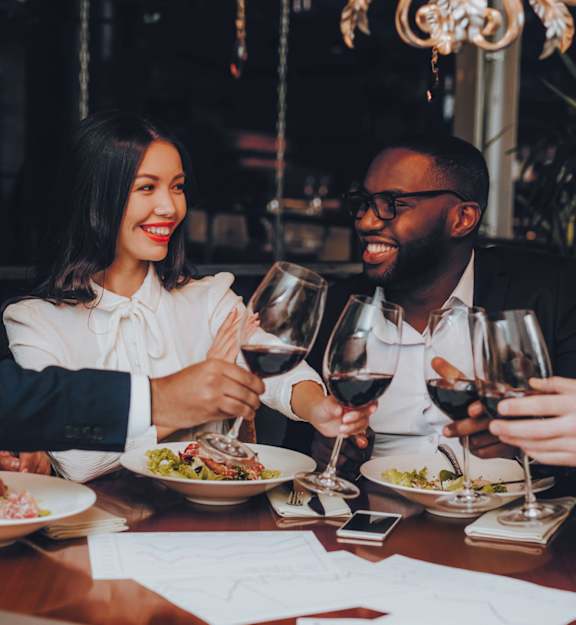 Four people toasting with wine glasses at a dinner table.