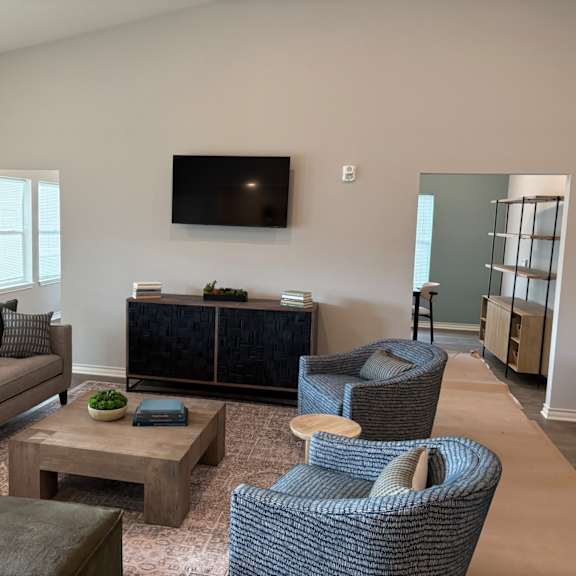 A living room with a grey sofa, a coffee table, and a television mounted on the wall.