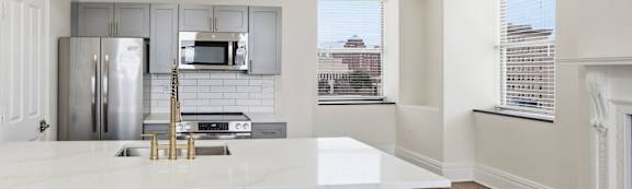 A kitchen with white cabinets and a white counter top.