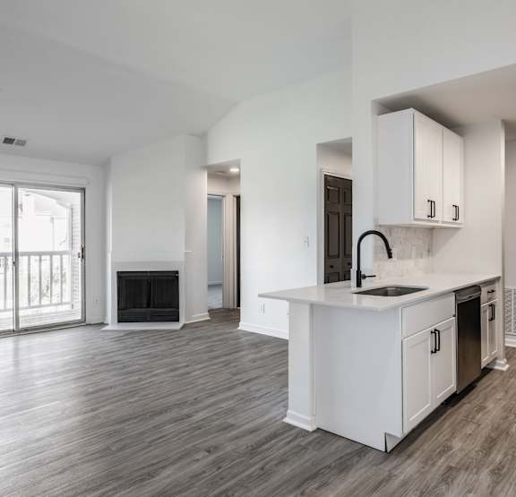 a living room with grey plank flooring, white walls, and a balcony at Sundance Apartments, Indiana, 46237